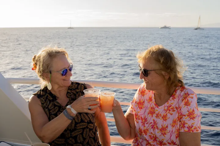 a group of people sitting on a boat with Mai Tai near a body of water
