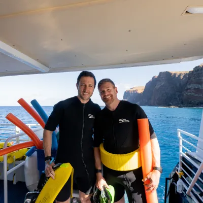 a man standing next to a body of water posing for the camera