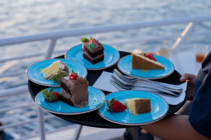 a blue and white cake on a plate next to a cup of water