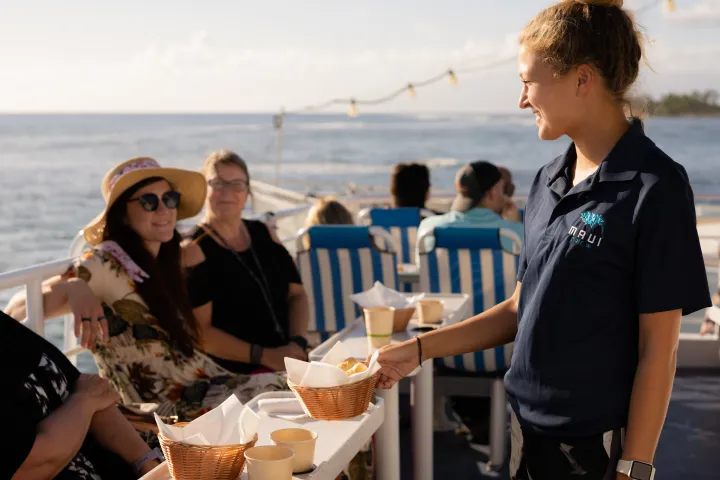 a group of people sitting at a table with food and water