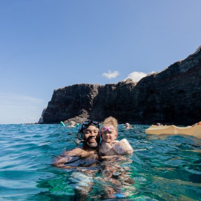 a man swimming in a body of water with a mountain in the background