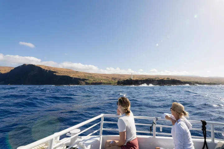 a woman standing in front of a snorkel spot and a lighthouse and giant sea cliff in the background